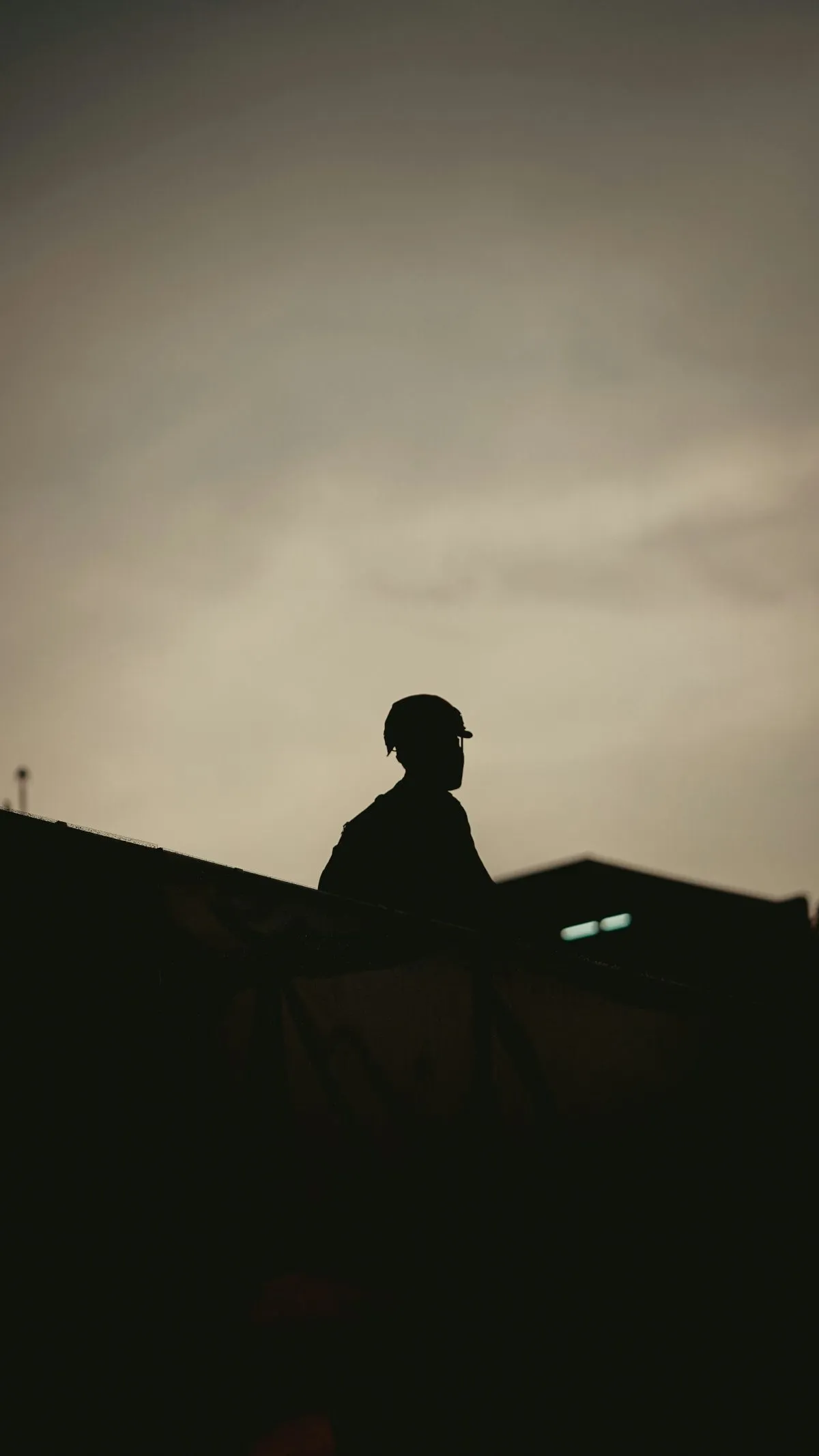 Silhouette of a worker in a hard hat against an evening sky on a job site